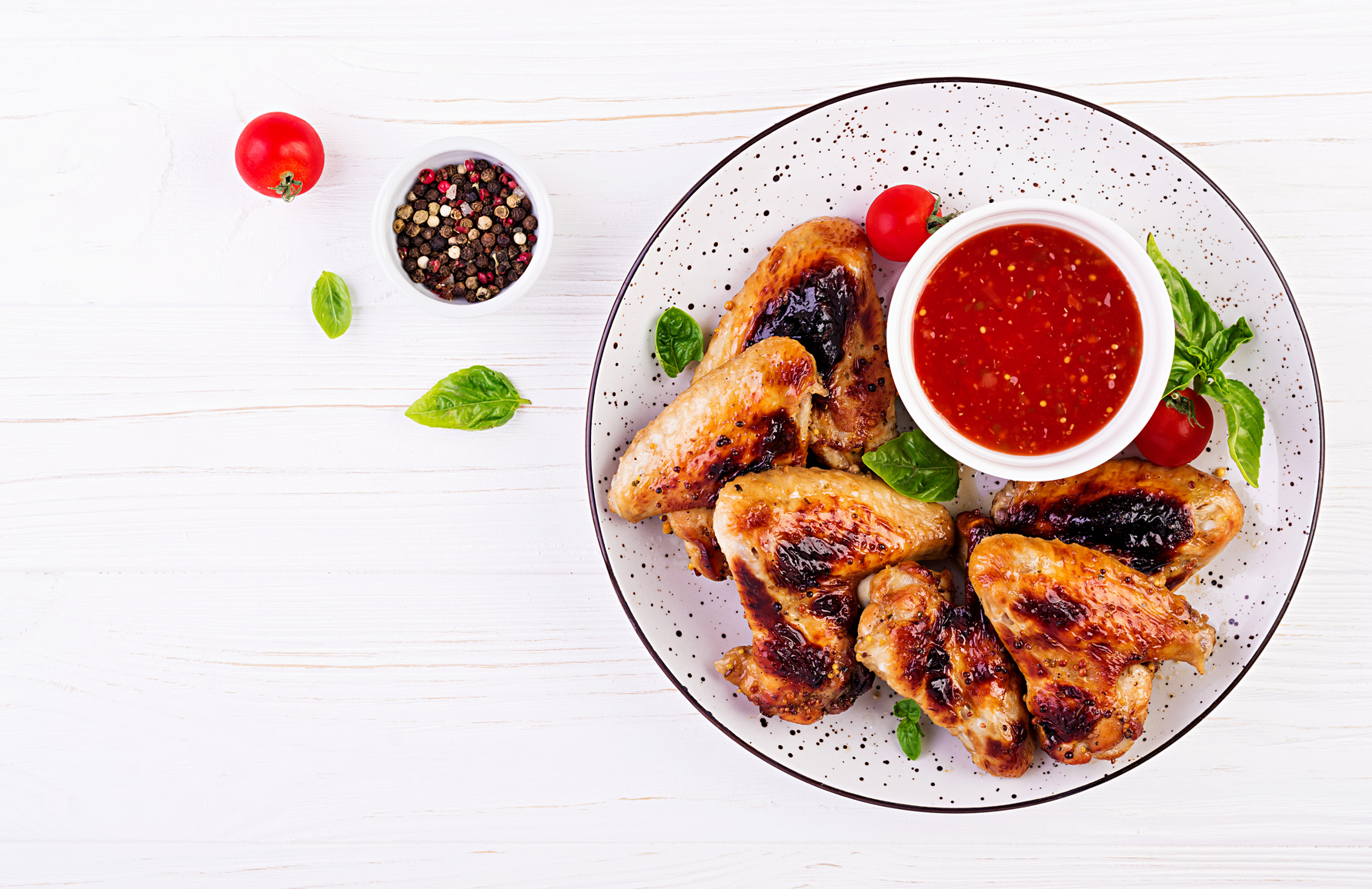 grilled chicken wings with tomato sauce on a white plate